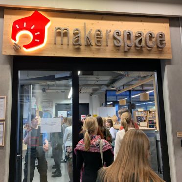 Eine kleine Gruppe Frauen betritt eine Raum durch eine Glastür. Über der Tür steht der Name "makerspace"