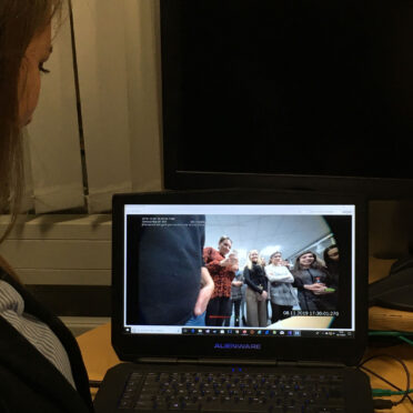 Eine junge Frau betrachtet den Bildschirm eines aufgeklappten Laptops.