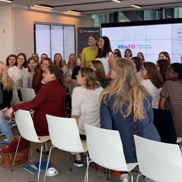 Judith Gerlach steht inmitten einer Gruppe junger Frauen und posiert für ein Gruppenfoto.