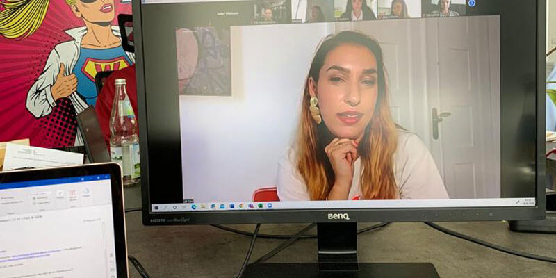 Personal-Branding-7 Ein Monitor steht auf dem Boden, daneben ein Laptop. Auf dem Monitor ist Tijen Onaran im Gespräch zu sehen.